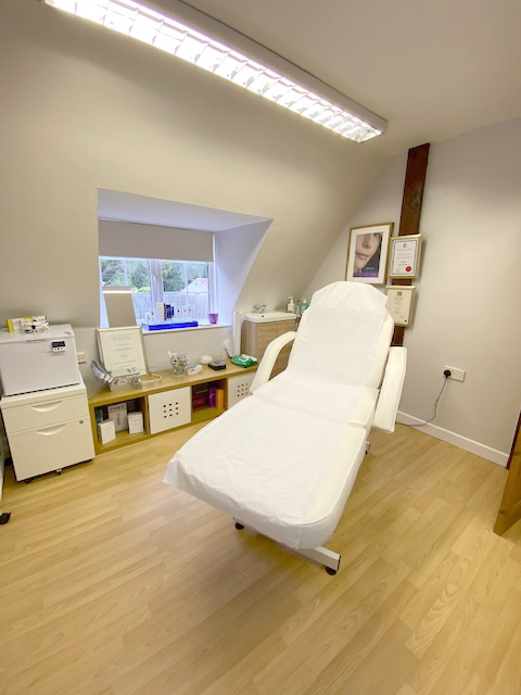 Imafge of treatment room at Dermedicare skin clinic and aesthetics clinic in Swanland near Hull in East Yorkshire. Light wooden floor with treatment couch against  lightwalls with light from window.